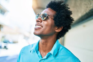 Genç, yakışıklı, Afro-Amerikan bir adam. Günlük kıyafetler ve güneş gözlüğü takıyor. Mutlu gülümsüyor. Yüzünde tebessümle kasaba caddesinde yürürken yan tarafa bakıyor..
