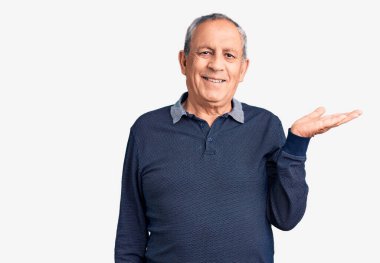 Son sınıf yakışıklısı sıradan polo giyen neşeli bir şekilde gülümseyen ve avuç içi kameraya bakan bir adam.. 