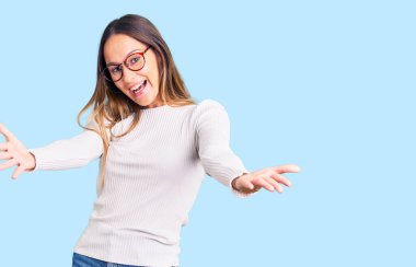 Güzel esmer, beyaz süveter giyen ve gözlüklü, neşeli gülümseyen genç bir kadın yardım eli uzatıyor ve kabul ediyor.. 