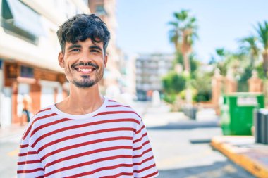 Genç İspanyol adam gülümsüyor Mutlu bir şekilde yürüyor şehrin caddesinde.