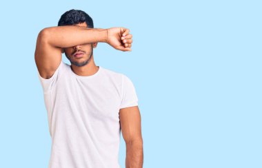 Gündelik kıyafetler giyen, kollarıyla gözlerini kapatan, ciddi ve üzgün görünen genç bir latin. Görme, saklama ve reddetme konsepti 