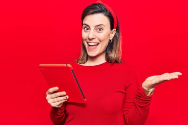 Genç ve güzel bir kadın dokunmatik yastığını tutarak başarıyı mutlu bir gülümsemeyle ve kazanan bir ifadeyle kutluyor. 