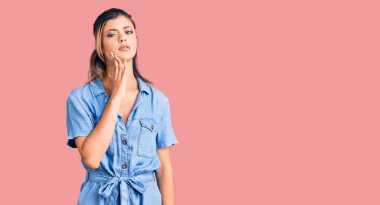 Genç ve güzel bir kadın diş ağrısı ya da diş hastalığından dolayı ağızlarına acı dolu bir ifadeyle dokunuyor. dişçi 