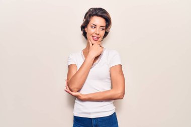 Elleri çenesinde gündelik giysiler giymiş soru soran, düşünceli bir kadın. Düşünceli bir yüzle gülümsüyor. şüphe kavramı. 