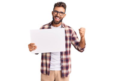 İspanyol asıllı genç adam boş bir pankart tutuyor gururla bağırıyor, zaferi kutluyor ve başarıyı kollarını kaldırarak kutluyor. 