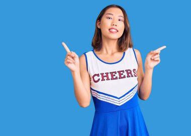 Ponpon kız üniforması giyen, kendine güvenen, farklı yönleri gösteren genç, güzel Çinli bir kız. reklam için kopyalama alanı 