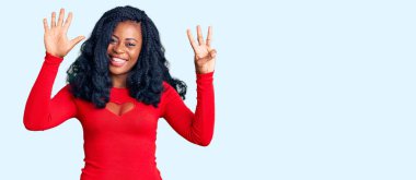 Güzel afro-amerikan kadın gündelik kıyafetler giyiyor ve 8 numaralı parmaklarıyla işaret ediyor kendinden emin ve mutlu bir şekilde gülümsüyor. 