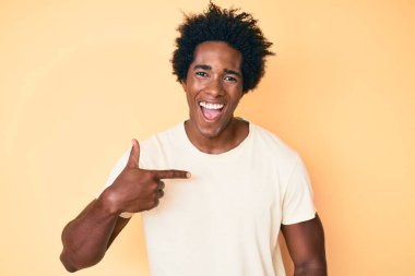 Yakışıklı, afro saçlı, kendini gösteren, gülümseyen ve kahkahalarla gülen Afro-Amerikan bir adam.. 