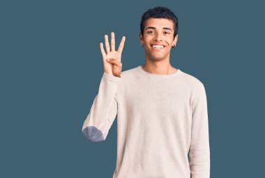 Genç Afrikalı Amerikalı günlük kıyafetler giymiş dört numarayı gösterip işaret ederken kendinden emin ve mutlu bir şekilde gülümsüyor.. 