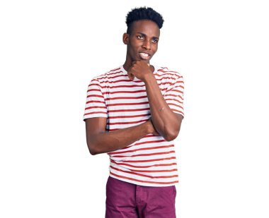 Elleri çenesinde gündelik giysiler giyen genç Afro-Amerikan bir adam soru soruyor, düşünceli bir ifade. Düşünceli bir yüzle gülümsüyor. şüphe kavramı. 