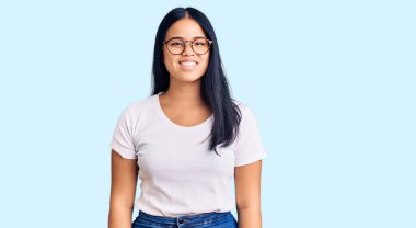 Genç, güzel Asyalı bir kız. Günlük kıyafetler ve gözlük takıyor. Yüzünde mutlu ve havalı bir gülümseme var. şanslı kişi. 