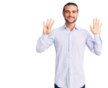 İş kıyafetleri giymiş genç yakışıklı adam dokuz numarayı gösterip işaret ederken kendine güvenen ve mutlu bir şekilde gülümsüyor.. 