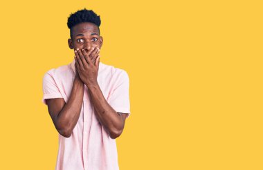 Gündelik giysiler giyen genç Afro-Amerikan bir adam yanlışlıkla elleri ile ağzını kapatırken şok oldu. gizli kavram. 