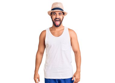 Yaz şapkası takan İspanyol genç adam komik bir ifadeyle mutlu bir şekilde dilini dışarı çıkarıyor. duygu kavramı. 
