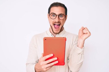 Genç yakışıklı adam dokunmatik bir cihaz kullanıyor. Gururla bağırıyor, zaferi kutluyor ve başarıyı kollarını kaldırarak kutluyor. 