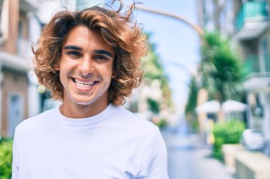 Genç, yakışıklı, gülümseyen bir İspanyol. Şehrin caddesinde mutlu bir şekilde yürüyor.