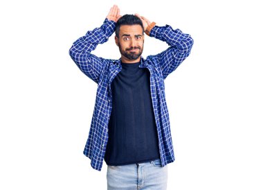 Gündelik kıyafetler giyen, tavşan kulağı yapan, avuçlarıyla alaycı ve şüpheci görünen genç İspanyol bir adam. Paskalya tavşanı konsepti. 