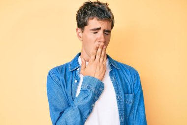 Gündelik kıyafetler giyen genç yakışıklı adam ağzıyla esnemekten sıkıldı. Huzursuz ve uykulu.. 