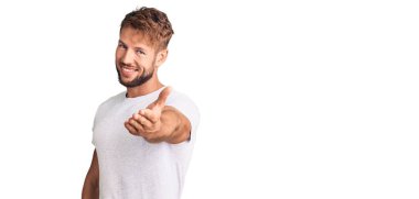 Beyaz bir tişört giyen genç beyaz bir adam dostça gülümseyerek selamlama ve hoş geldin diyor. başarılı iş. 