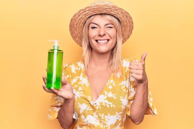 Yazlık şapkalı, elinde aloe vera kremiyle gülümseyen, mutlu ve pozitif gülümseyen güzel sarışın kadın.