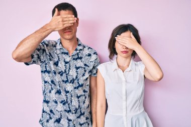 Güzel bir çift, gündelik giysiler giyip, elleriyle gözlerini kapatıyor, ciddi ve üzgün görünüyorlar. Görme, saklama ve reddetme konsepti 