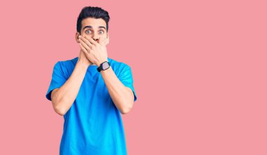 Sıradan tişörtler giyen sakallı genç yakışıklı adam yanlışlıkla elleri ile ağzını kapatırken şok oldu. gizli kavram. 