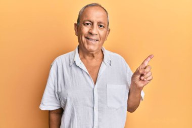 Yakışıklı, olgun, günlük beyaz gömlek giyen, gülümseyen, mutlu, eli ve parmağı yana doğru olan bir adam. 