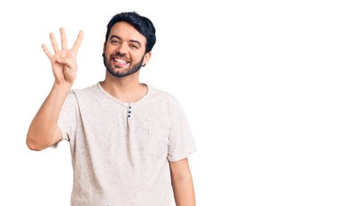 İspanyol asıllı genç adam, gündelik giysiler giyip dört numarayı gösterip işaret ederken kendinden emin ve mutlu bir şekilde gülümsüyor.. 
