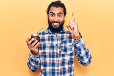 Genç Arap adam bir fikir ya da soruyla gülümsüyor ve mutlu bir yüzle işaret ediyor. 