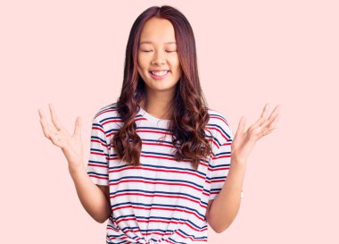 Genç, güzel Çinli kız, gündelik kıyafetler giyip başarıyı kutluyor. Kolları havada, gözleri kapalı, heyecanlı çığlıklar atıyorlar. Kazanan konsept 