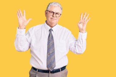 Yaşlı, gri saçlı, iş kıyafetleri giyen, dokuz numaralı parmaklarıyla işaret eden, kendinden emin ve mutlu bir adam.. 