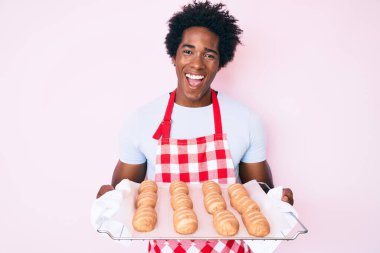 Afro saçlı, fırıncı üniforması giyen, elinde ev yapımı ekmek tutan ve kahkahalarla gülen yakışıklı Afro-Amerikan bir adam.. 