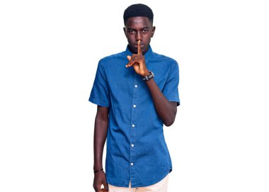 Gündelik giysiler giymiş genç Afro-Amerikan bir adam sessiz olmak istiyor. sessizlik ve gizli konsept. 