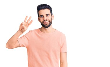 Sakallı, sıradan tişörtlü, üç numaralı parmaklarıyla gösteriş yapan, kendinden emin ve mutlu gülümseyen genç yakışıklı bir adam.. 