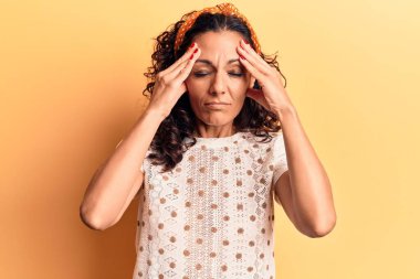 Orta yaşlı, güzel bir kadın. Elleri kafasında rahat bir tişört giyiyor. Stres yüzünden baş ağrısı çekiyor. migren ağrısı. 