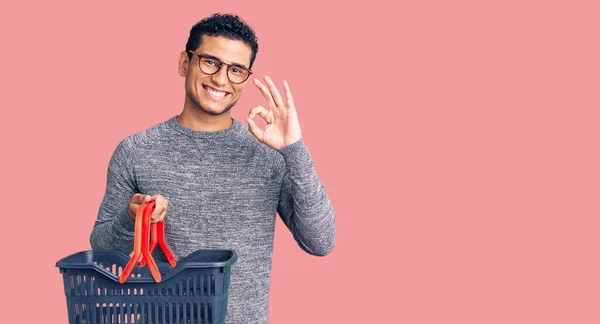 Hispano Joven Guapo Sosteniendo Cesta Compra Del Supermercado Haciendo Signo —  Fotos de Stock