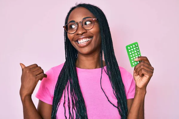 African American Woman Braids Holding Birth Control Pills Pointing Thumb — ストック写真