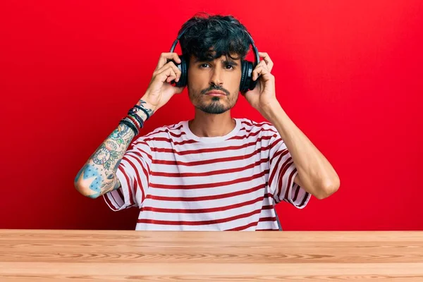 Junger Hispanischer Mann Mit Kopfhörern Der Deprimiert Auf Dem Tisch — Stockfoto