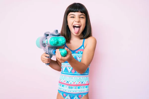 Kleines Mädchen Mit Knall Badeanzug Und Wasserpistole Streckt Die Zunge — Stockfoto