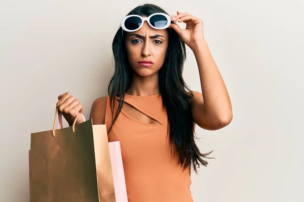 Hermosa Mujer Hispana Sosteniendo Bolsas Compras Con Gafas Sol Escépticas — Foto de Stock