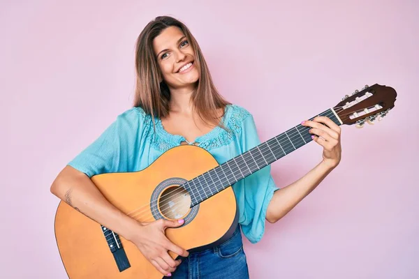 美丽的高加索女人在弹古典吉他时面带微笑 脸上带着快乐而凉爽的笑容 显示牙齿 — 图库照片