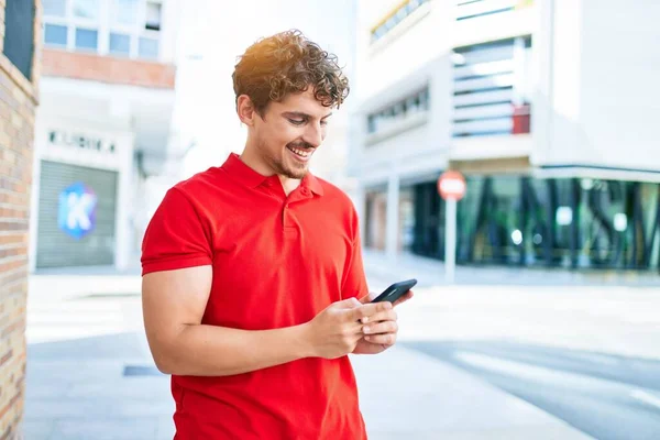 若いですハンサムな白人男性笑顔幸せな使用してスマートフォン歩行で街 — ストック写真