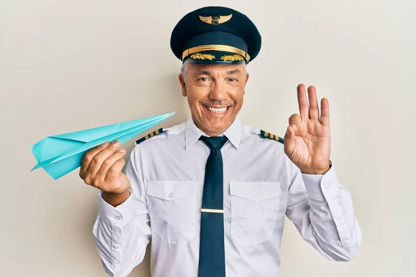 Schöner Mann Mittleren Alters Der Flugzeugpilotenuniform Trägt Papierflugzeug Hält Und — Stockfoto