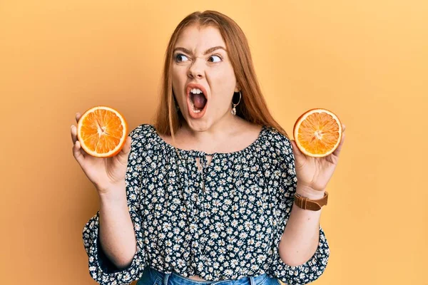 Mladá Krásná Zrzka Drží Čerstvé Pomerančové Plátky Rozzlobené Šílené Křičí — Stock fotografie