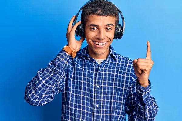 若いアフリカ系アメリカ人の男性は アイデアや質問を指差す指で笑顔ヘッドフォンを使用して音楽を聞いて幸せな顔 ナンバーワン — ストック写真