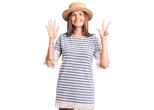 美しいです白人女性を身に着けています夏の帽子ショーと指番号8で指摘しながら 自信と幸せ笑みを浮かべて — ストック写真