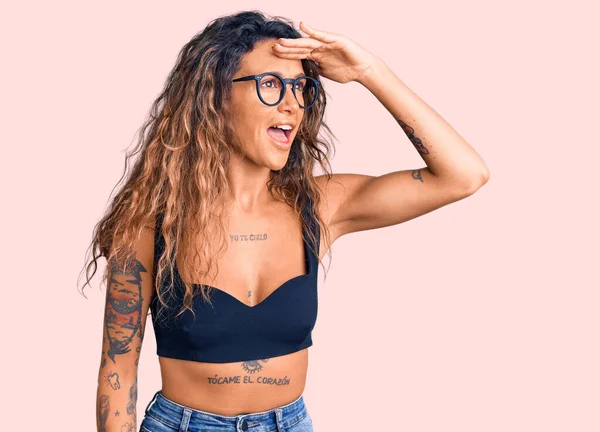 Günlük kıyafetler ve gözlük takan, mutlu ve gülümseyen dövmeli İspanyol bir kadın. arama kavramı. 