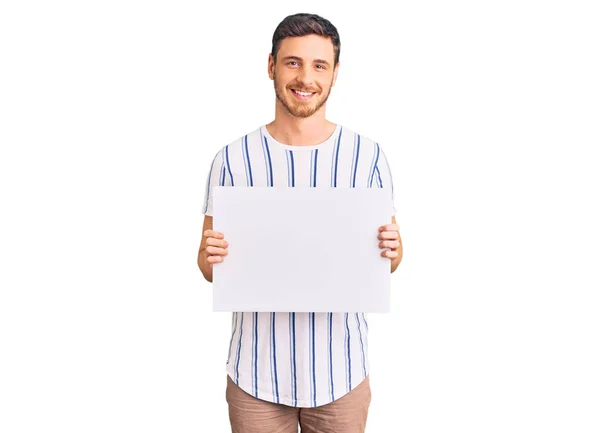 Joven Guapo Con Oso Sosteniendo Banner Vacío Blanco Mirando Positivo — Foto de Stock