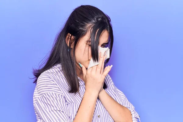 年轻的惊慌失措的女人用纸巾在鼻子上 站在孤立的紫色背景上 — 图库照片