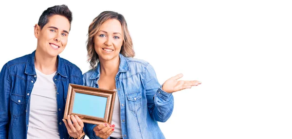 Couple Women Holding Empty Frame Smiling Cheerful Presenting Pointing Palm — Stock Photo, Image